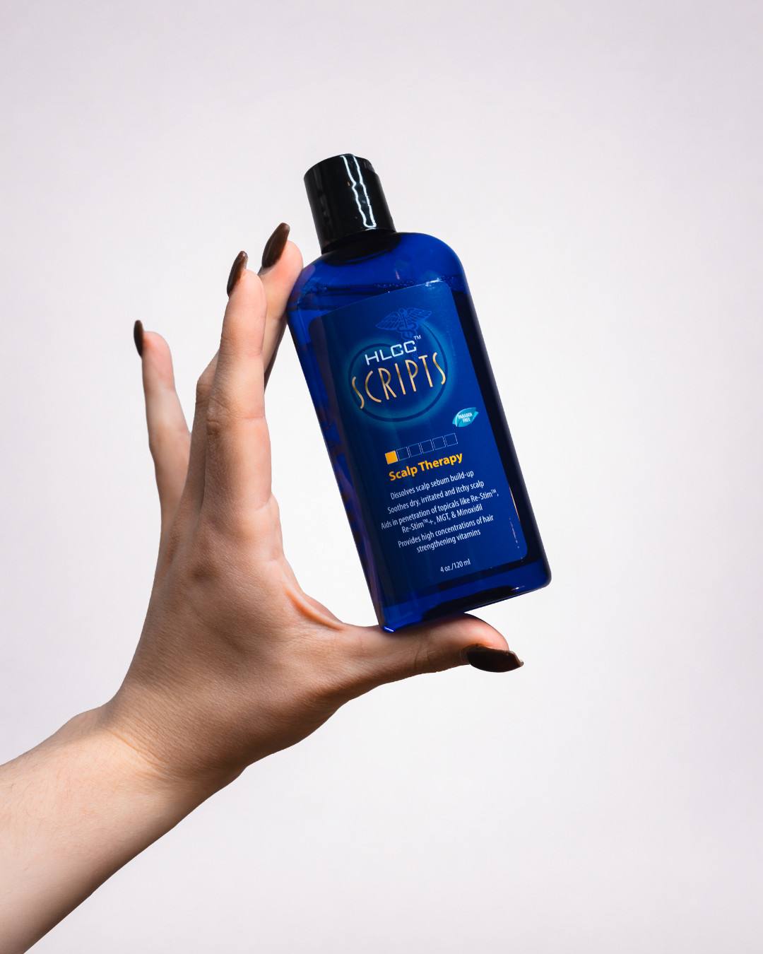 Hand holding HLCC Scripts Scalp Therapy bottle